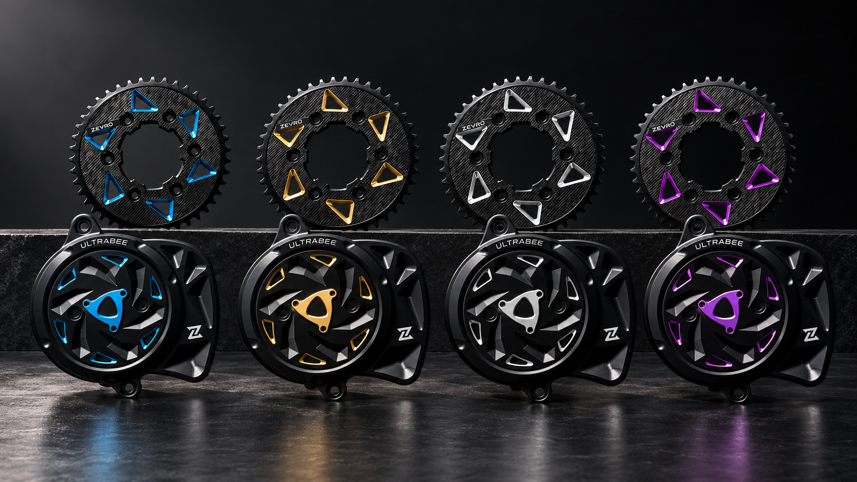 Spectra carbon sprockets and matching Vortex motor covers in blue, gold, silver and purple, arranged in a dark studio